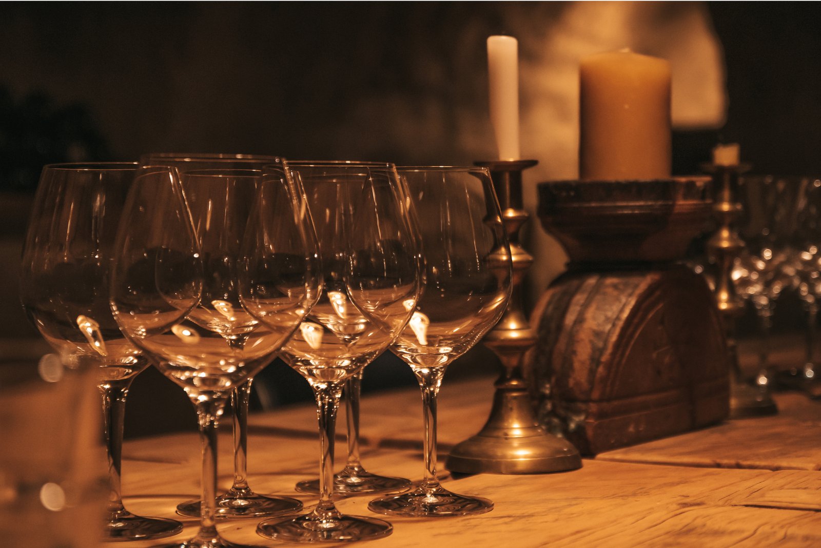 Wine glasses arranged on a rustic wooden table by warm candlelight at Jackson Estate