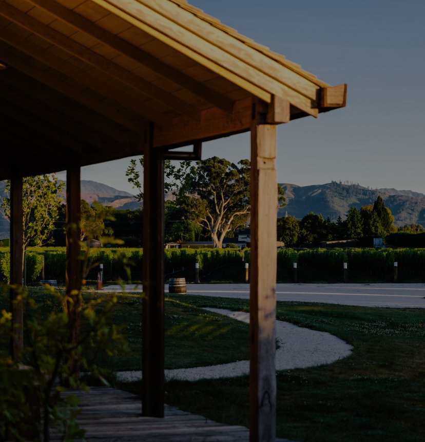 Covered outdoor deck at Jackson Estate with vineyard grounds, oak barrel, and mountain ranges at golden hour