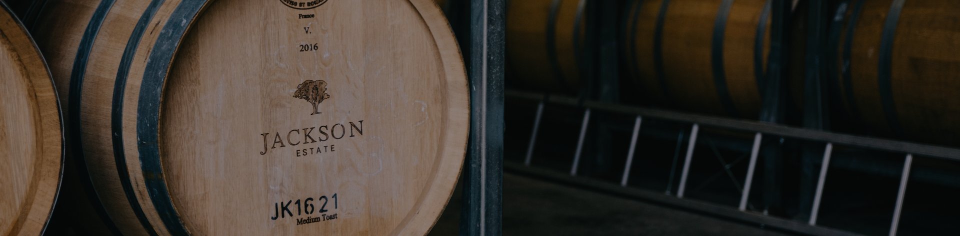 Jackson Estate wine barrels stacked in a cellar, with barrel code JK1621 visible on the closest barrel